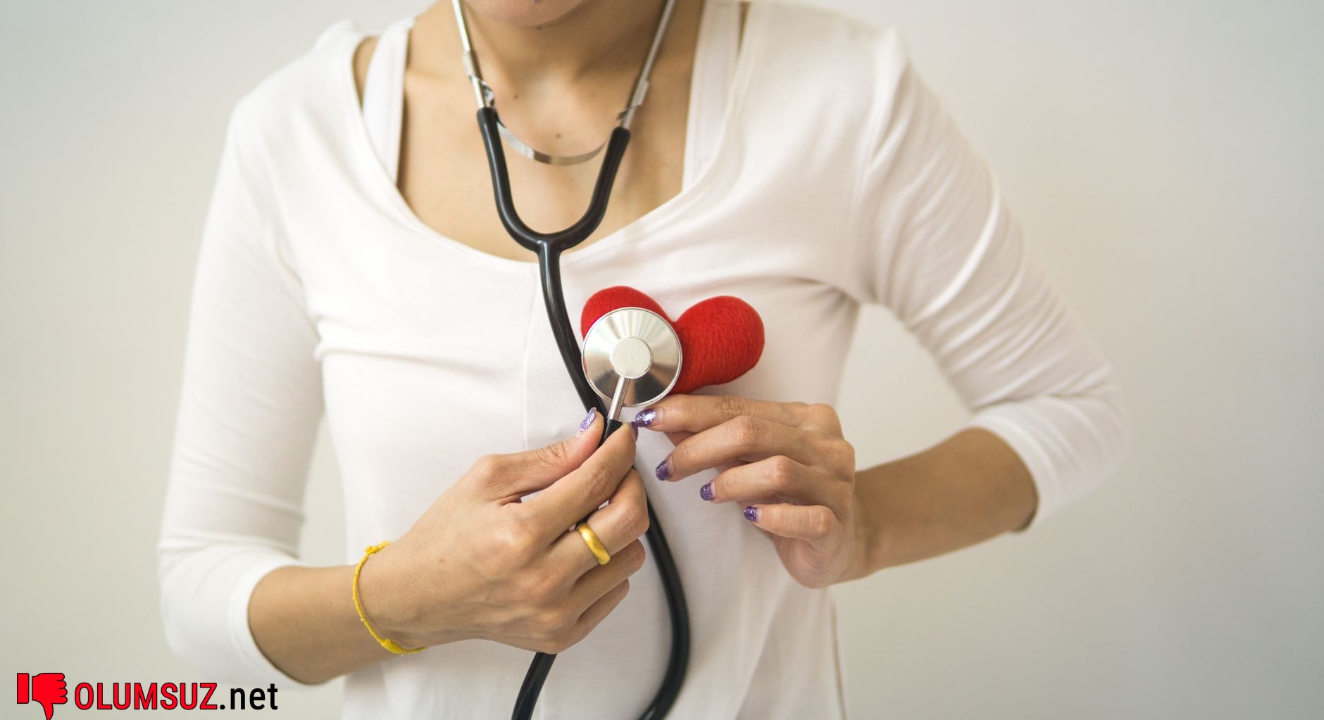 Doktor stetoskopla nabız ölçüyor, EKG sonuçları arka planında